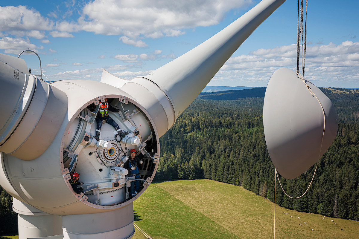 Vue aérienne du montage de la dernière éolienne du parc de Romande Energie à Sainte-Croix, avec techniciens dans la nacelle, le 1ᵉʳ septembre 2023.