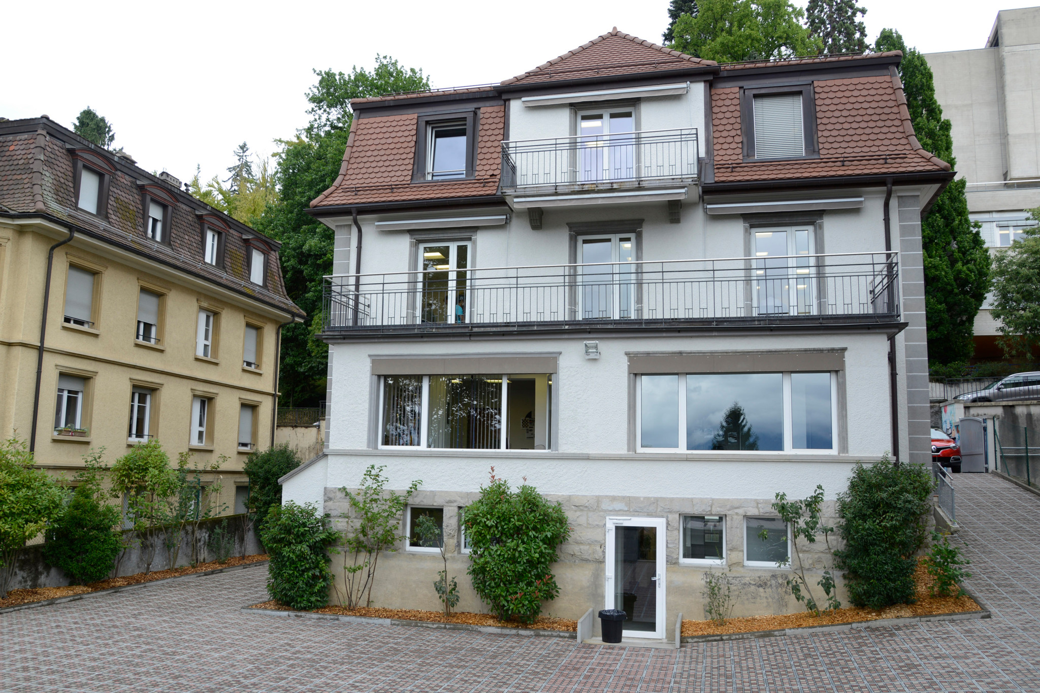 Façade de l’école La Garanderie à Lausanne, bâtiment blanc de trois étages avec balcons et toiture en tuiles rouges.