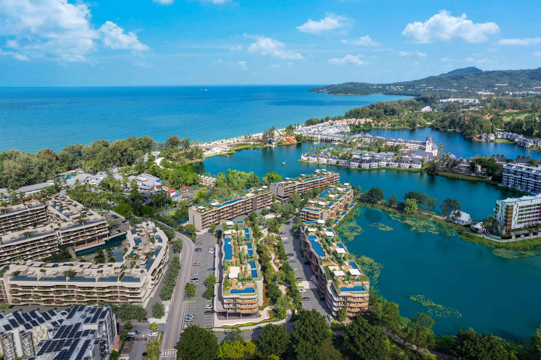 Vue aérienne d’un complexe résidentiel moderne en bord de mer, entouré de lacs et de végétation tropicale luxuriante sous un ciel bleu.