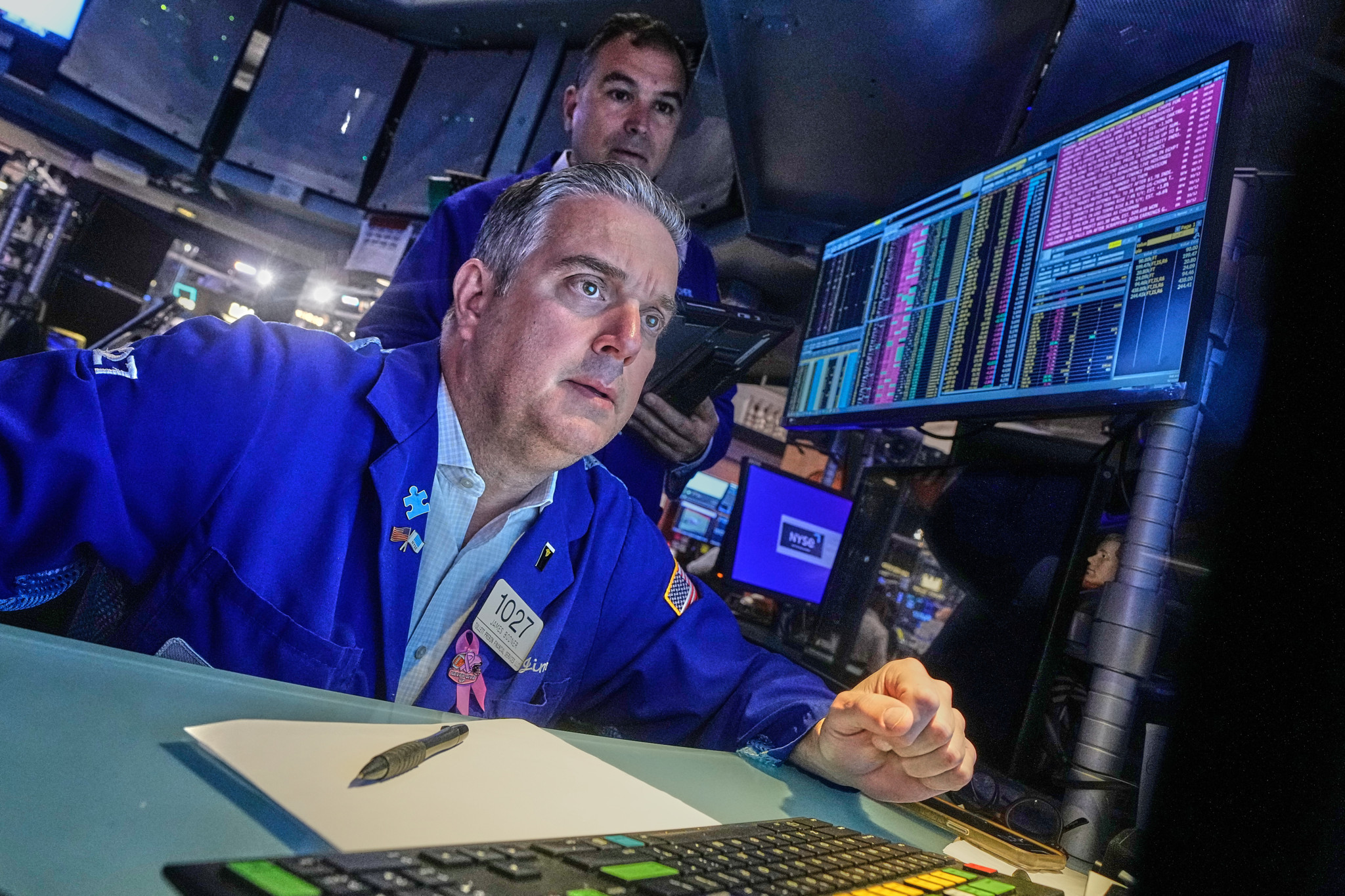 Des traders travaillent sur le plancher de la Bourse de New York avec des écrans d’ordinateur affichant des données financières.