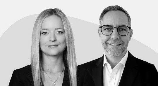 Portrait en noir et blanc d’une femme aux cheveux longs et d’un homme portant des lunettes, tous deux en tenue professionnelle.