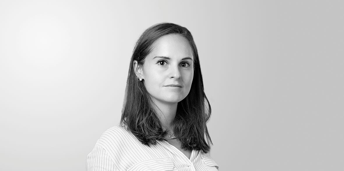 Portrait en noir et blanc d’une jeune femme aux cheveux mi-longs, portant une chemise rayée, sur fond clair.