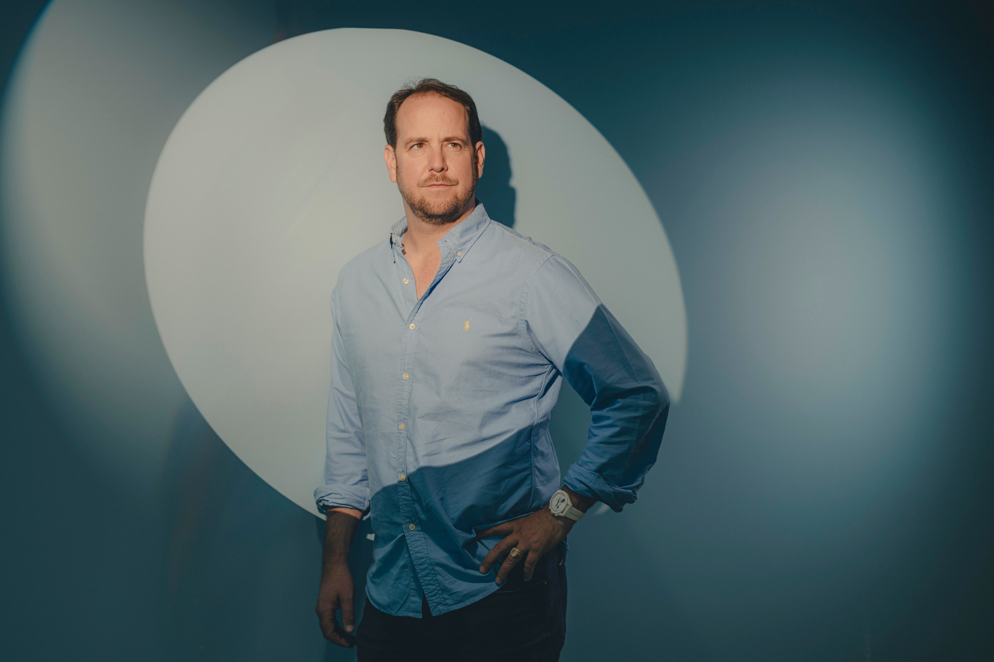Guillaume DuPasquier, cofondateur et PDG de Domo.Health, en chemise bleue, posant devant un fond sombre avec un cercle lumineux.