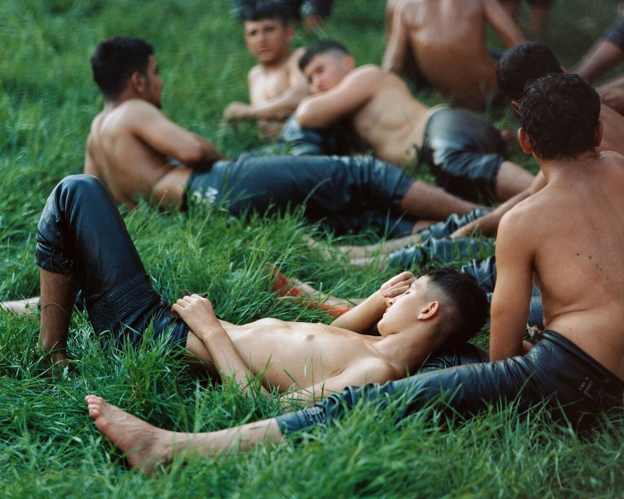 Jeunes lutteurs torse nu en pantalons de cuir noir se reposant sur l’herbe verte lors d’un tournoi de lutte à l’huile turque