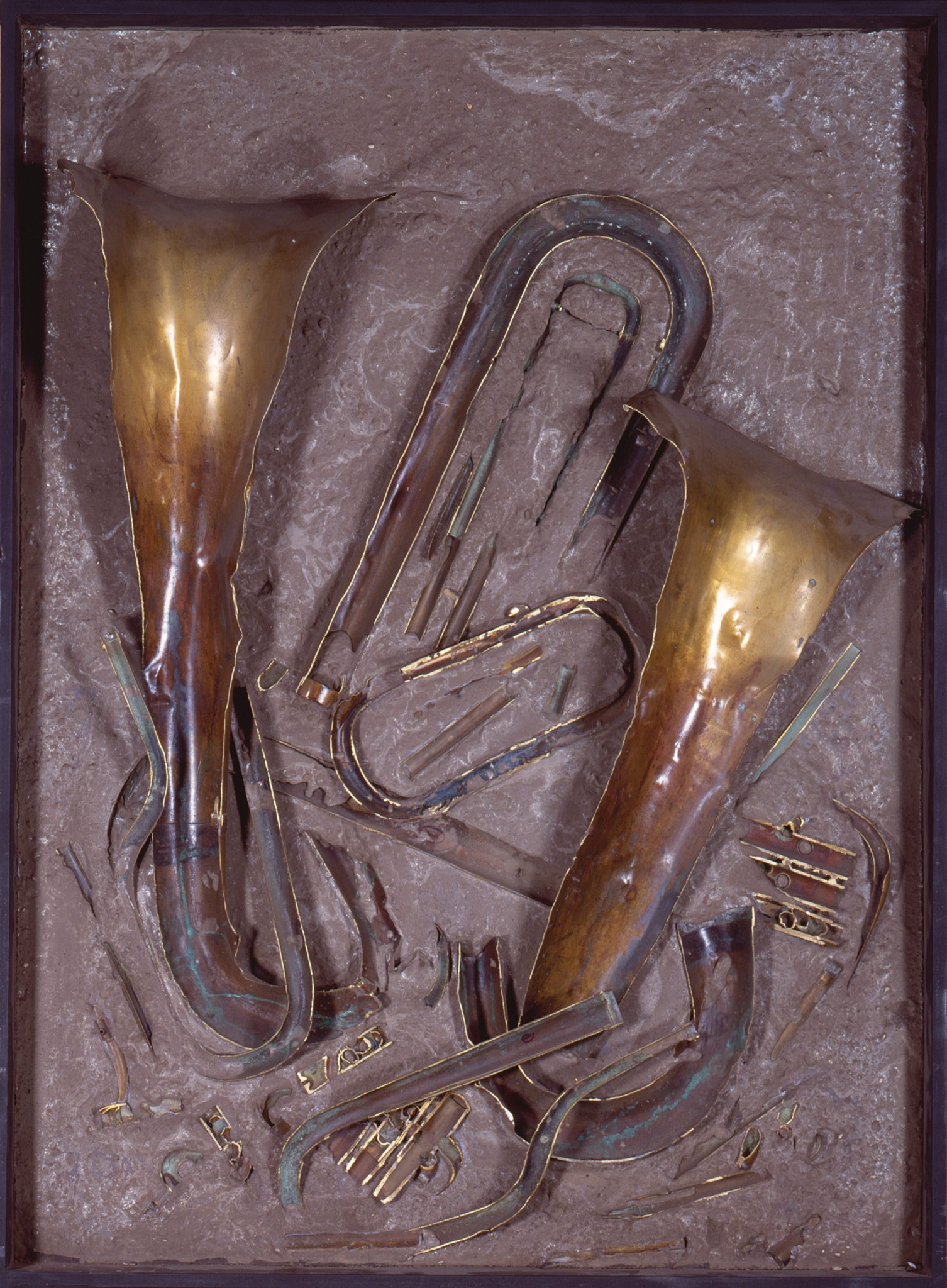 Sculpture en relief représentant des instruments à vent en laiton doré et cuivre, partiellement enfouis dans une surface texturée gris-brun.