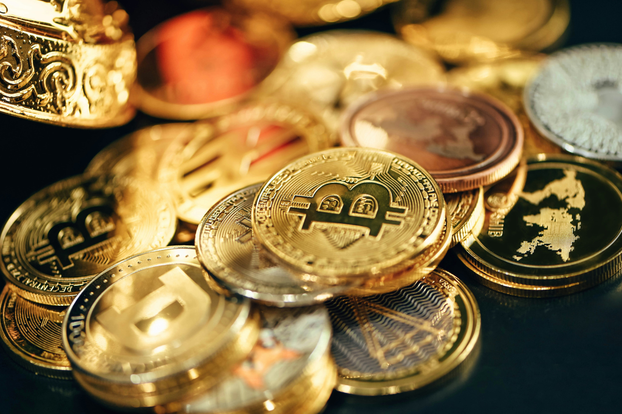 Collection de pièces de cryptomonnaie dorées et argentées, avec des symboles de bitcoin et autres devises numériques.