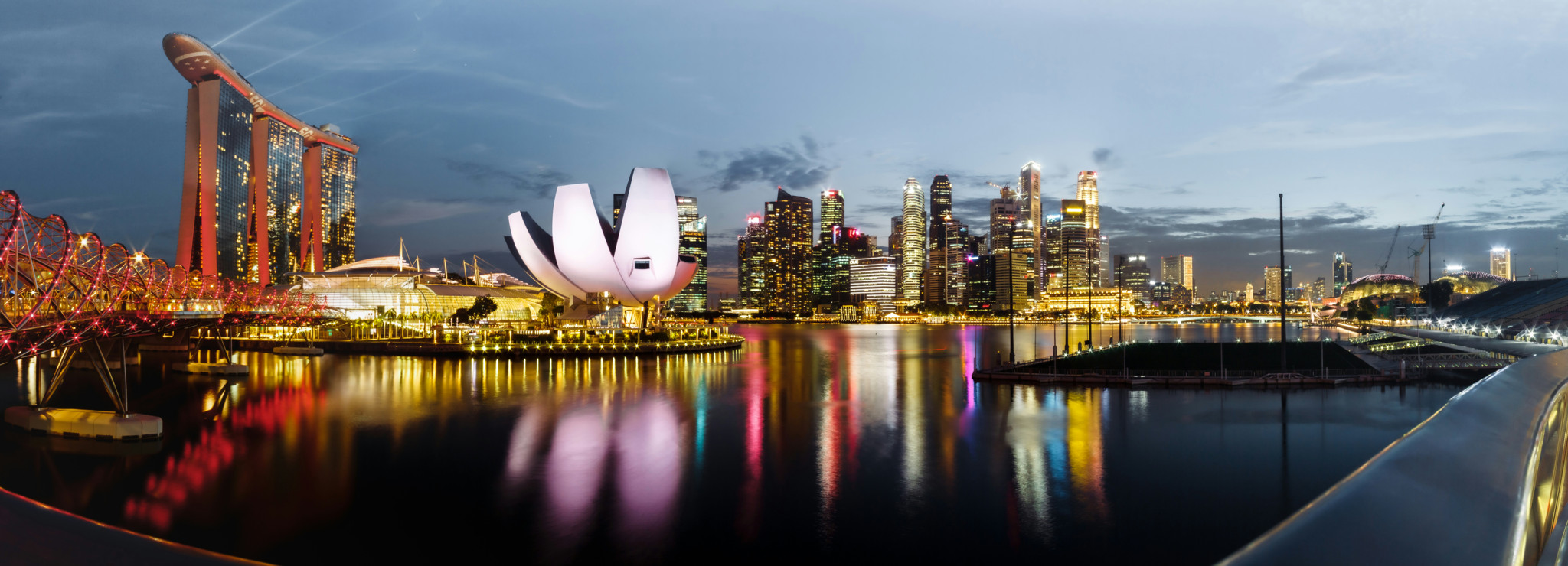 Panorama nocturne de Singapour avec le Marina Bay Sands, l’ArtScience Museum et les gratte-ciels illuminés se reflétant dans l’eau